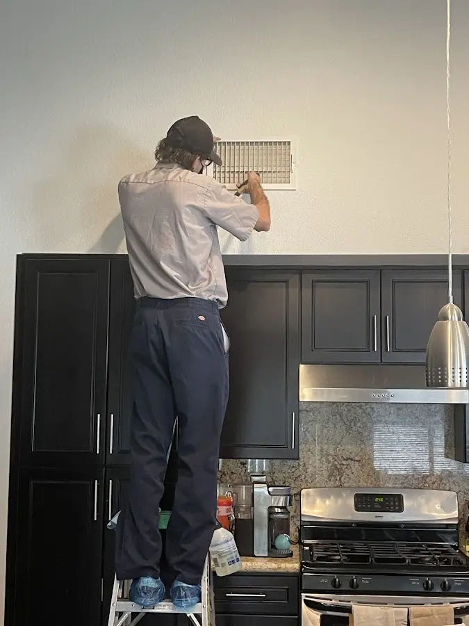 Technician inspecting an air vent during HVAC service in Anaheim